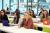 A front view of students sat in a lecture, in front of large glass windows.