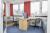 A bedroom with two single beds on either side of the room and two desks dividing the room in the middle.