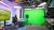 A person sits at a desk in a modern studio with a green screen backdrop, professional lighting, and cameras. "University of Westminster" is displayed on a screen.