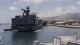 A big boat transporting food docking in the sea in front of some mountains