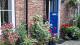 Blue front door with lots of plants in the front garden