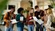 Happy female student showing test results to her friends while standing in a lobby