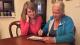 A younger and older woman sitting around a table doing a crossword.