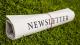 Image of a newsletter rolled up on the grass