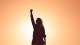 Person celebrating with fist in the sky and sunset background