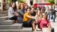 Westminster students sitting on stairs in Central London with red double decker buses in the background