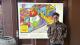 Student Amy Grant standing in front of her artwork, which is a drawing of a second hand street.