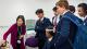 A group of school pupils are being shown an experiment on the brain. One pupils is wearing a brain scanning device and the other pupils are watching behind him in amazement.