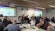 Several tables in a room looking at projector boards which read: Robots for Construction - A Case Study