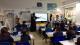 Westminster students delivering a workshop to pupils sat in rows of desks at Queens Park Primary School.