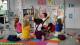 Children with their hands in the air sat around a teacher