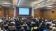 Photo of Karen Powell from ADR introducing the conference to a full audience. Behind her is a projector screen which reads: Why we are here and various reasons why the research is important.
