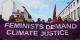Banner reading “Feminists demand climate justice” held by protesters during a street demonstration, with flags and buildings visible in the background.