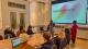 A team pitching their idea in front of a projector at the Hellenic Centre