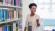 A student smiling next to library books