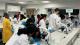 Students in lab coats examining particles under microscopes in a lab.