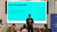 Peter Bonfield presenting at the event in front of a projector screen which reads Peter Bonfield OBE Vice-Chancellor and President, University of Westminster