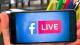 Hand holding mobile phone with Facebook Live on screen