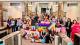 University of Westminster students and staff pose for a group photo at the Pride Breakfast event, wearing colourful rainbow attire and holding Pride flags.