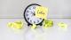 Clock surrounded by crumpled post-it notes, one reading 'later'.