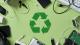 Dark green recycling logo on a light green background surrounded by electronic goods