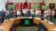 Photo of commissioners standing in parliament around a U-shaped wooden table