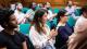Picture of the audience clapping. They are sat on green chairs in a wood-panelled room.