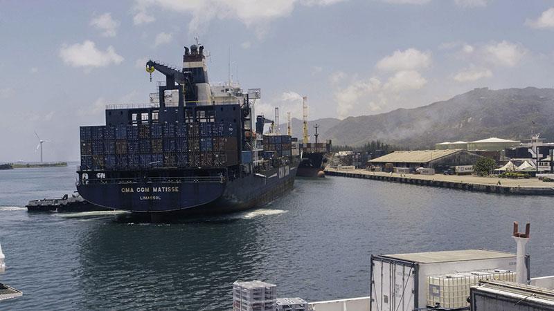 A big boat transporting food docking in the sea in front of some mountains