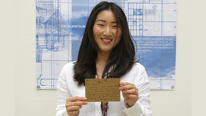 Girl with black hair holding a postcard at the University of Westminster