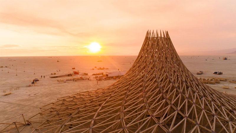Arthur Mamou-Mani's Galaxia project, a swirly wooden tower, in the desert with the sun setting