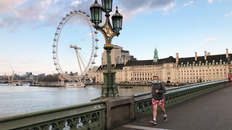 Brisk walker in mask on Westminster bridge during lockdown