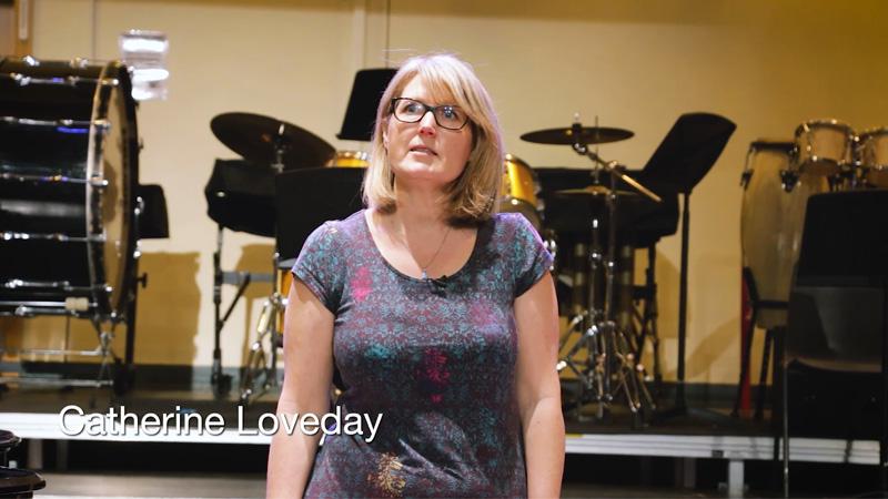 Professor Catherine Loveday delivering TEDx talk with musical instruments in background