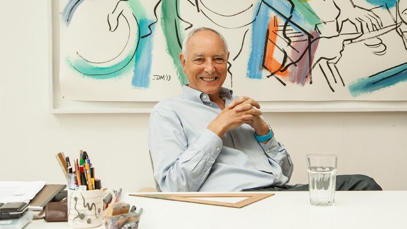A photo of Chris Wilkinson sat at a desk and smiling.