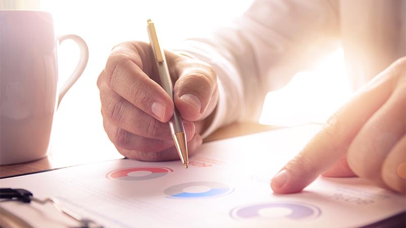 Close up picture of a businessman studying a report with a cup of coffee on the side, Image by PureSolution