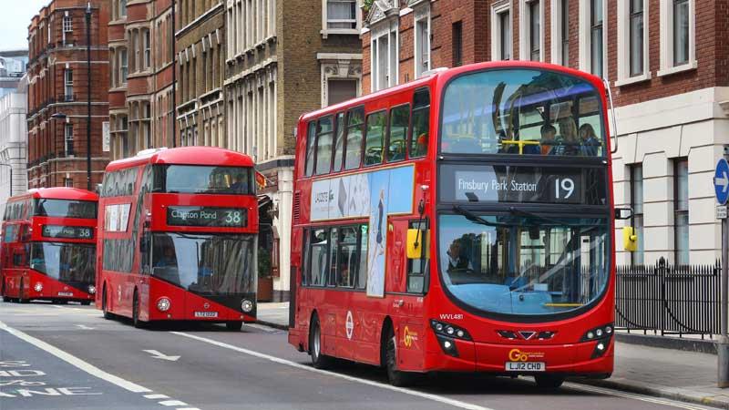 Double decker buses driving down the road in London