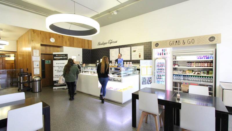 A café with tables, chairs a food counter and a drinks fridge