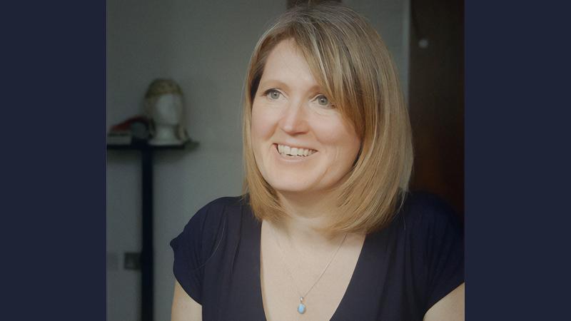 Head shot of Catherine Loveday wearing a dark blue dress with silver necklace