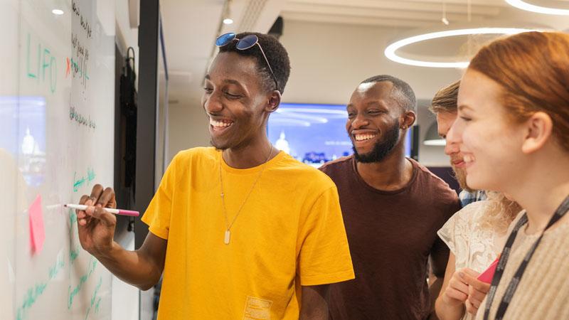 Students smile while looking at whiteboard.