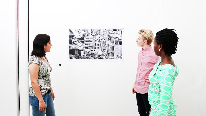 Students looking at work exhibited on a white gallery wall
