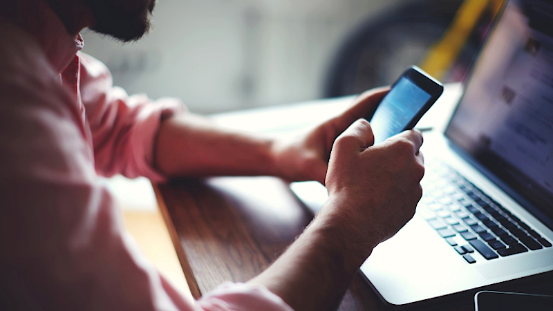 Man-using-phone-and-laptop