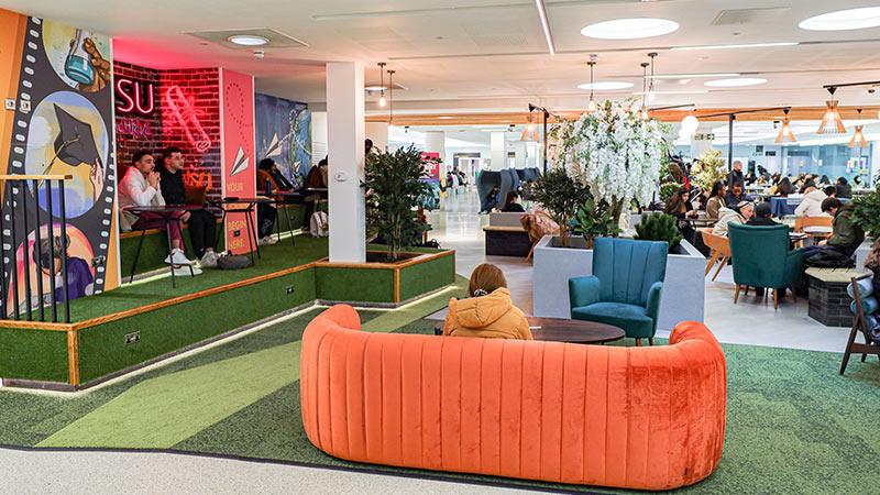 Marylebone students' space in front of Sumiya's mural with seats and tables and orange couches