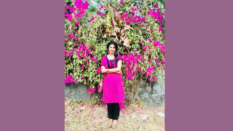 Professor Nitasha Kaul in front of bright pink flowers in Kerala
