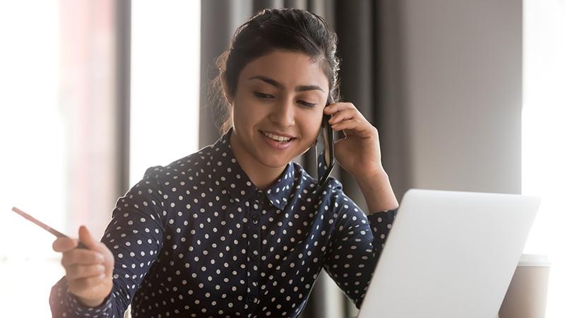 A person smiling whilst talking on a telephone.