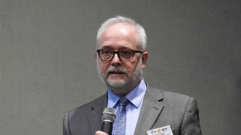 Terry Lamb speaking at a conference in front of a grey screen