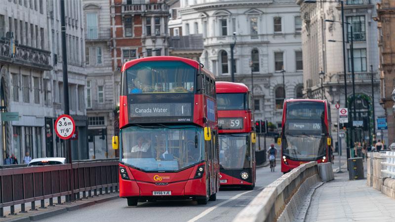 Three London buses driving on the road