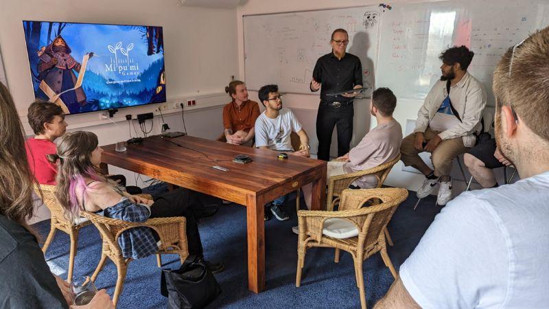 Group of students around a table listening to a speaker