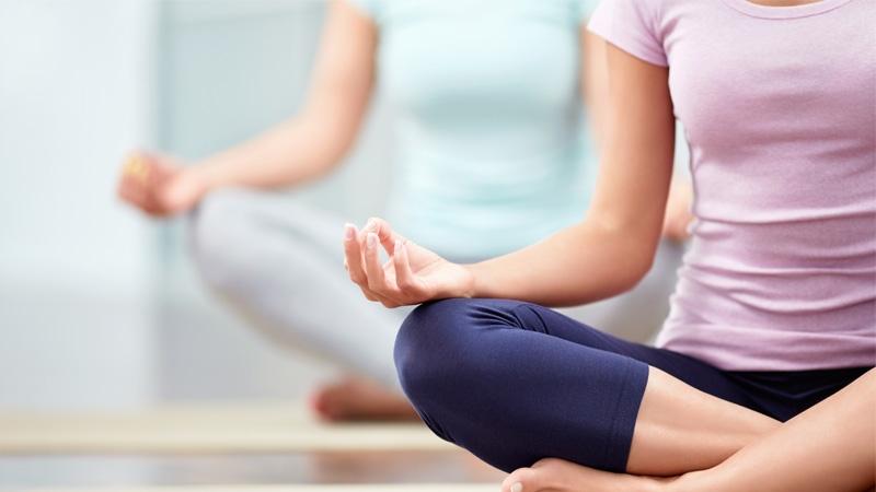 Two ladies sitting crossed legged doing yoga