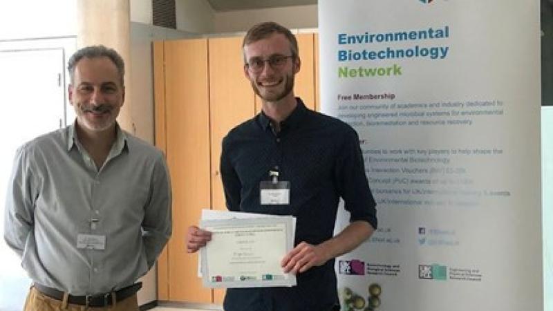 Alumnus Kyle Bowman holding certificate for his winning poster.