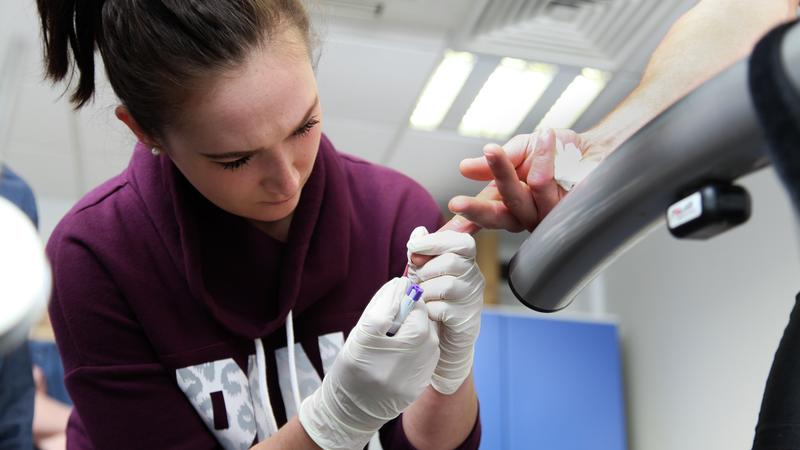 A female taking blood from a finger