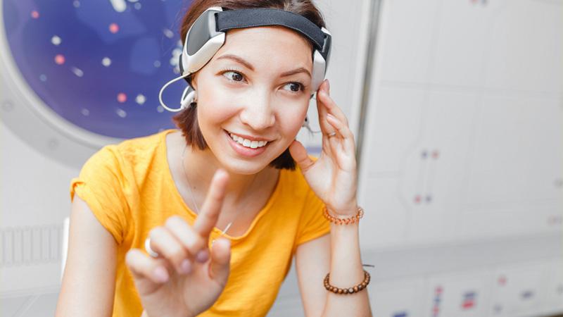 Woman with digital headwear equipment sensor connected to her ear, reading brain impulses.